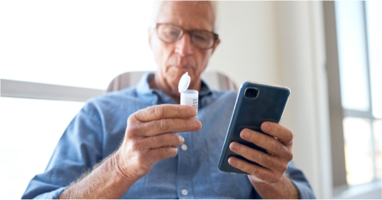 Senior man holding cell phone and glucose strip container