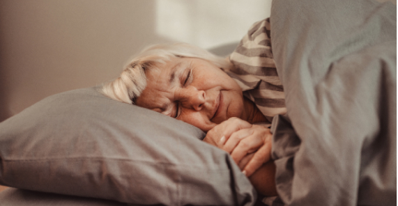 Older woman sleeping in bed with her head on the pillow