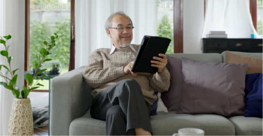 Senior man sitting on couch and using a tablet device